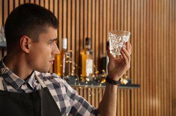 Male bartender wiping whiskey glass at workplace