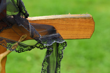 Close-up and background of a simple wooden cross in a Christian graveyard with a black ribbon
