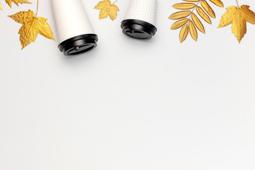 Fototapeta premium Coffee or tea paper cups, golden autumn leaves on light gray background top view flat lay. Take away coffee cup, mockup. Coffee love, layout for design. Fall concept. Autumn background. Copy space