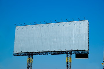 Blank aluminium billboard on blue sky background, ready for new advertisement.