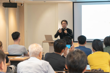Fototapeta premium Asian Speaker is speaking on the stage over the presentation screen in the education seminar