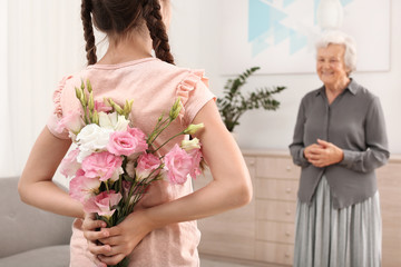 Obraz na płótnie Canvas Girl congratulating her grandmother at home, closeup
