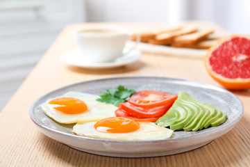 Plate with fried eggs and vegetables on wooden table. Healthy breakfast