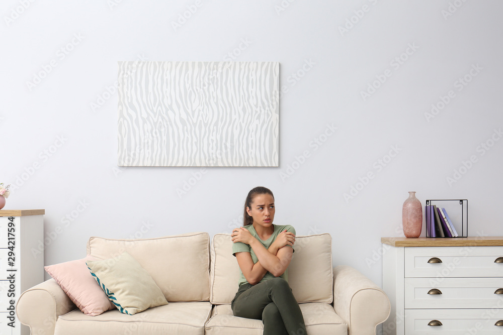 Wall mural young woman freezing under air conditioner at home