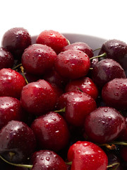 A bowl full of freshly washed cherries on white.