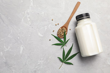 Flat lay composition with bottle of hemp milk on grey marble table. Space for text