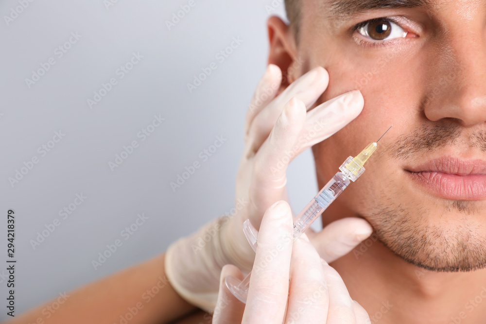 Wall mural man getting facial injection on grey background, closeup. cosmetic surgery