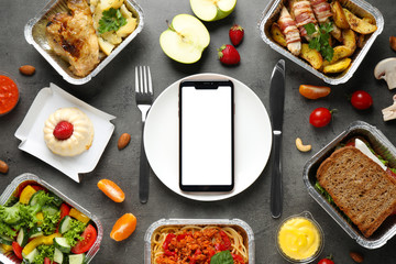 Flat lay composition with lunchboxes and smartphone on grey table, mockup for design. Healthy food delivery