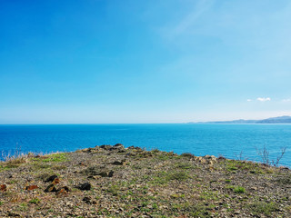 Fototapeta na wymiar The edge of the rocky shore overlooking the endless horizon in the sea..