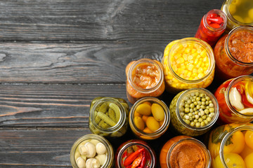 Jars of pickled vegetables on black wooden table, flat lay. Space for text