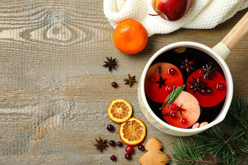 Saucepan with tasty mulled wine on wooden background, flat lay. Space for text