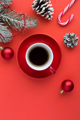 Obraz na płótnie Canvas Black coffee in the red ceramic cup and Christmas composition on the red background. Copy space. Top view. Location vertical.
