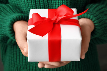Woman holding beautiful Christmas gift with bow, closeup