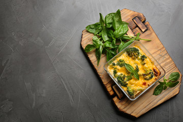 Tasty broccoli casserole in baking dish on grey table, top view. Space for text