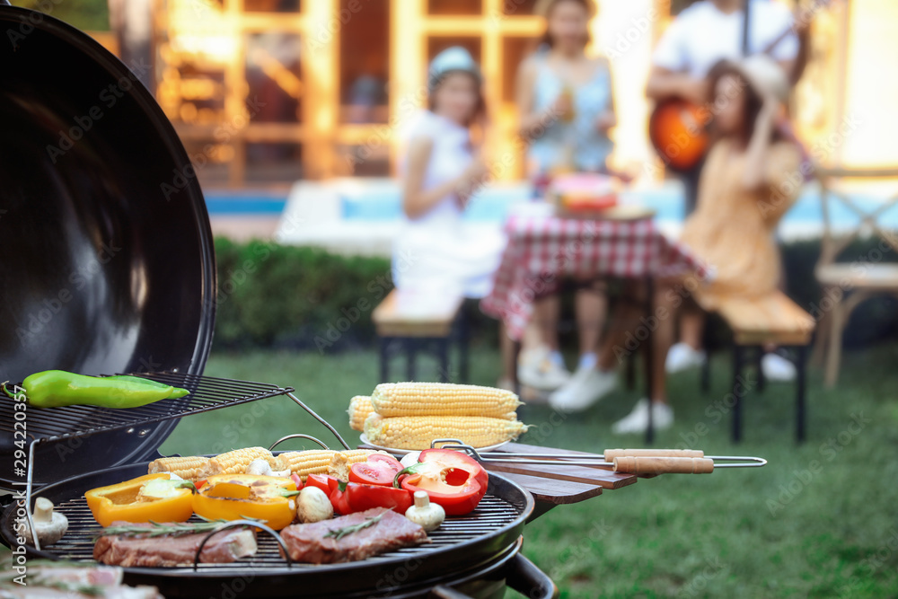 Wall mural Barbecue grill with tasty fresh food and blurred people on background