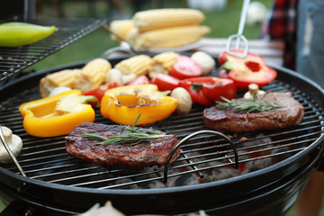 Barbecue grill with meat and vegetables outdoors, closeup