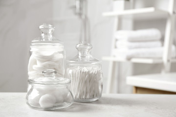 Cotton balls, swabs and pads on light grey table in bathroom