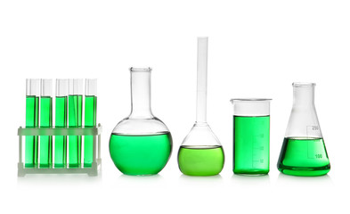 Laboratory glassware with green liquid on white background