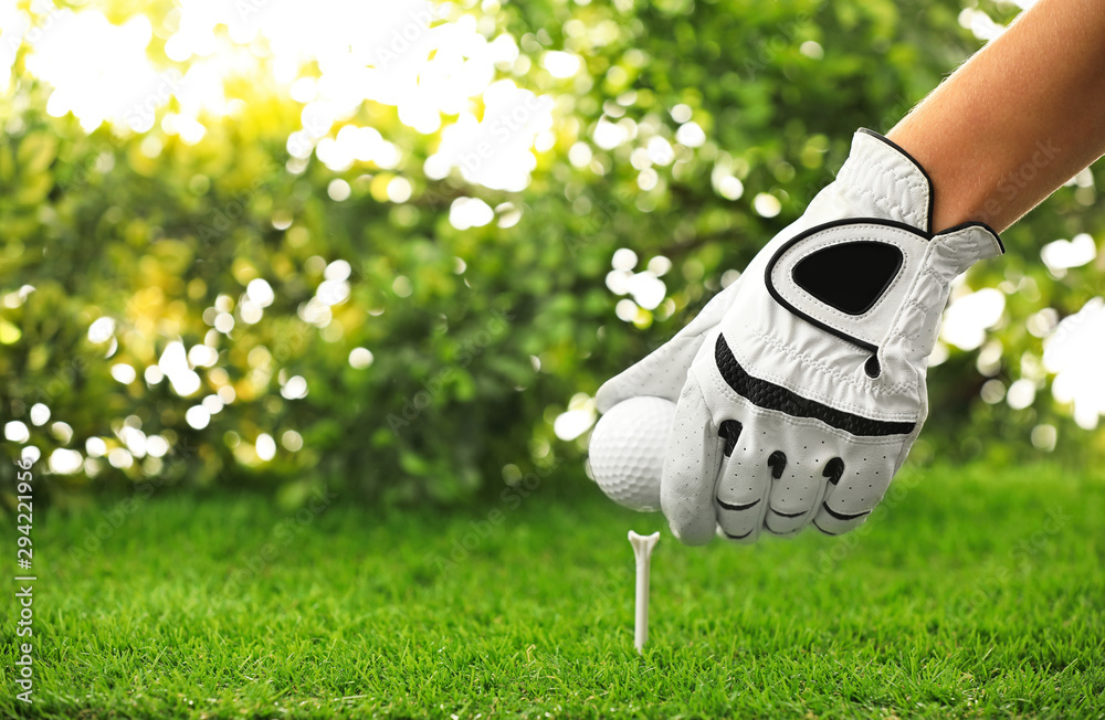 Wall mural Player putting golf ball on tee at green course, closeup