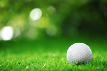 Golf ball on green grass against blurred background