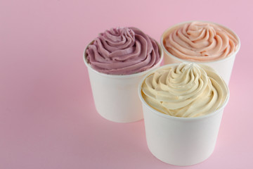 Cups with tasty frozen yogurts on pink background