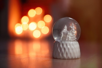 Fototapeta na wymiar Snow globe on wooden table against blurred background, space for text. Bokeh effect