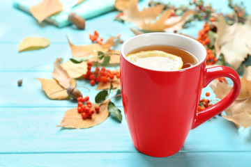 Cup of hot drink and leaves on blue wooden table. Cozy autumn atmosphere