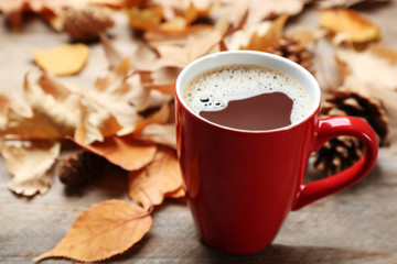 Cup of hot drink and leaves on wooden table. Cozy autumn atmosphere