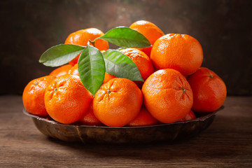 Fresh mandarin oranges fruit or tangerines with leaves in a bowl