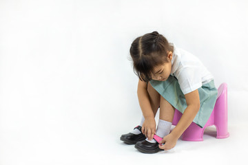 Little kid practice put on the socks and shoes to dressing by herself. Learning to do activity daily living help the kids developt their self esteem and confident.