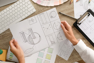 Female designer working at wooden table, top view