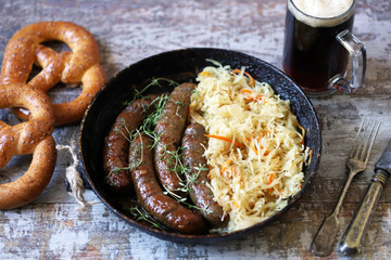 Bavarian sausages in a pan with stewed sauerkraut. Oktoberfest food. Selective focus. Macro.