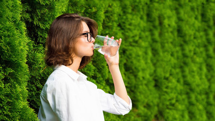 Close up young modern woman drinks water in the garden.
