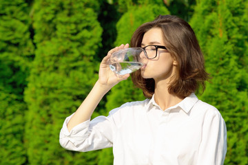 Young woman drinks water in garden