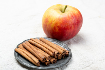 Winter pastry food ingredient, dried aromatic cinnamon sticks and apple on tin plate