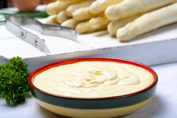 White hollandaise sauce in bowl, traditional sauce for dishes with cooked white asparagus