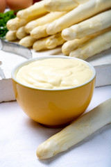 White hollandaise sauce in bowl, traditional sauce for dishes with cooked white asparagus