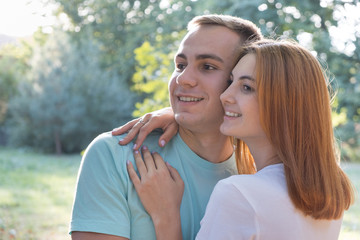 Young teenage couple outdoors. Pretty girl with red hair and handsome boy hugging together.