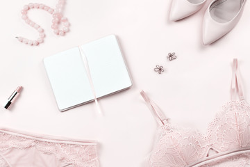 Woman lace lingerie, shoes and jewelry flat lay in pastel light pink color. Elegant, glamorous bra and panties set, pumps layout, fashion for women concept. Copy space, top view
