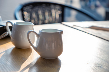 Two white cups of coffee on a table of outdoor cafe.
