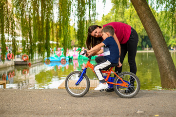Mother Teaching her Son to Ride a Bike in Park