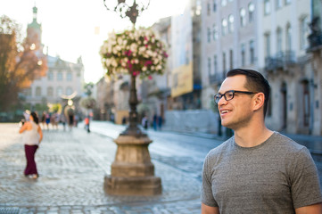 Outdoors portrait of an excited male tourist in the street with buildings of an old town in Europe in the background