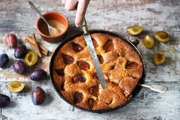 Men's hands cut plum pie with knife and fork. Homemade plum pie. Autumn cooking. Selective focus. Macro.