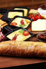 Delicious traditional Swiss melted raclette cheese on diced boiled or baked potato and baguette served in individual skillets with salami..