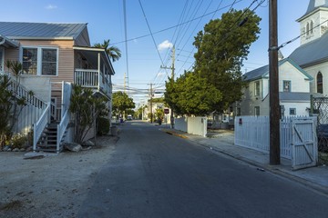 View of one of streets of Key West. Old houses and big green trees on blue sky background. Key West. Florida. USA.