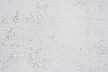 Concrete wall texture with small cracks carelessly painted with white paint