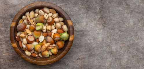 Banner of Tasty almonds, hazelnutss,pumpkin seeds,pistachios in wooden bowl on old wooden background with copyspace. Top view