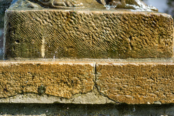 Stone, heavily textured pedestal about which drops of water are broken