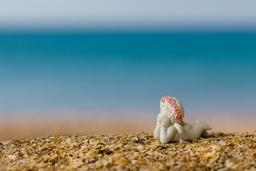 ceramic angel on the beach by the sea under the tropical sun. Sea vacation concept
