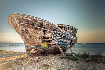 An old wooden fishing boat covered in graffiti on dry dock.